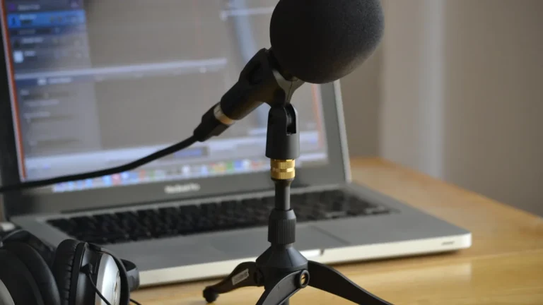 Condenser microphone and headphones on a desk in a small recording space